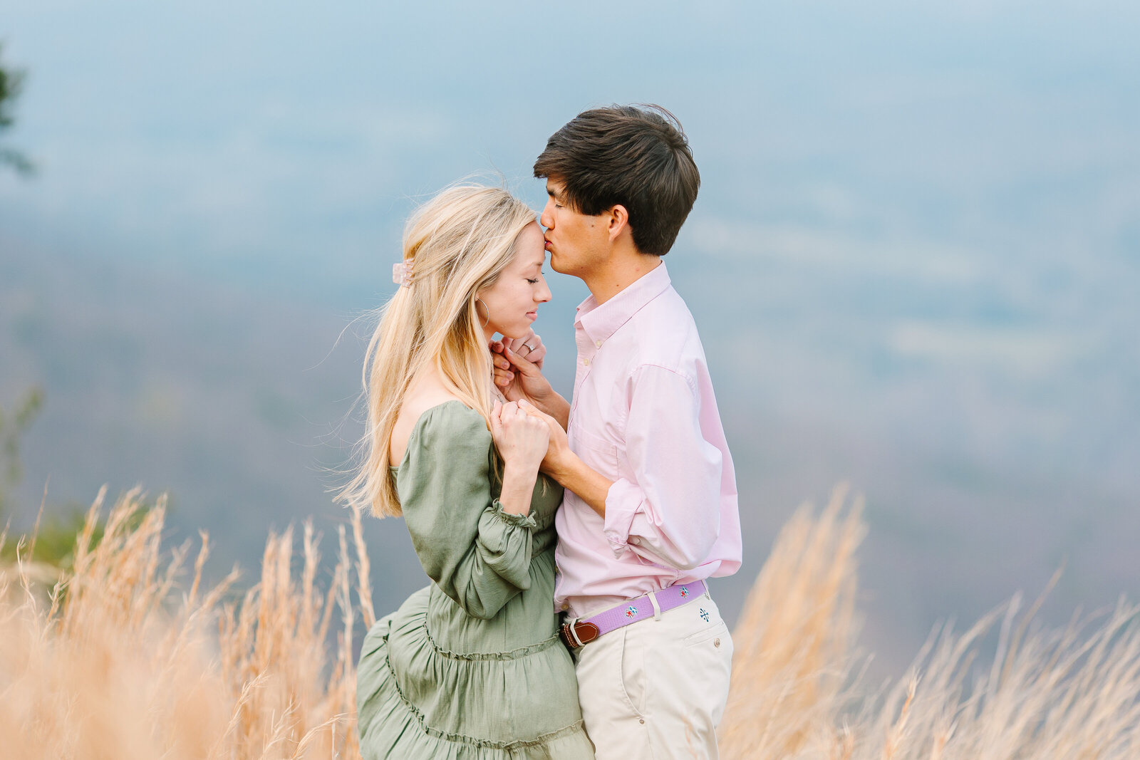 Couple embracing in tall golden grass on a mountain overlook