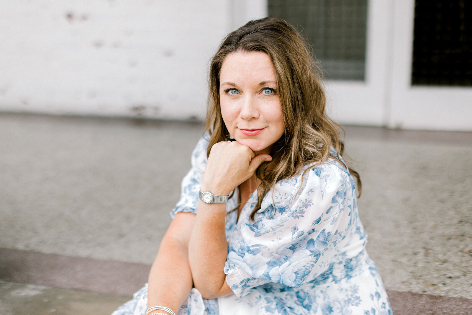 Mandy Hart, Knoxville wedding and portrait photographer, sitting on a step in a blue floral dress